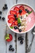 A smoothie bowl with strawberries, blackcurrants and muesli