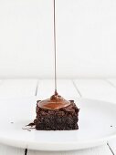 Chocolate sauce being drizzled onto a brownie