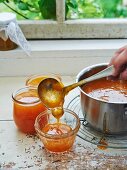 Filling glass jars with apricot jam