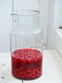 Ingredients for raspberry jam in a glass jug