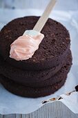 Making a chocolate cake: spread the cake with strawberry cream