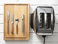 Assorted kitchen utensils: cutlery, a vegetable peeler and a toaster