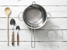 Assorted kitchen utensils: spoons, a saucepan, a sieve and a glass bowl