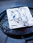 Barbecue food in a close aluminium dish on a barbecue