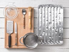 Kitchen utensils: a grater, a citrus press, a saucepan, a pastry brush and a grill tray