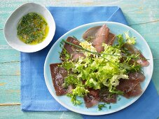 Frisee lettuce on a bed of ham carpaccio