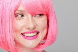 A young woman with a pink-coloured wig and lipstick