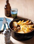 Beef casserole topped with sliced potatoes in a casserole dish