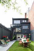 Black house with terraces and colourful, stylish courtyard garden