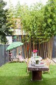 Sommerlicher Innenhof Garten mit langem Holztisch und Bambus