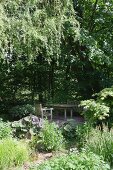 Lauschiger Gartenplatz mit Holzmöbeln unter Laubbäumen