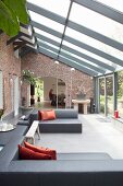 Designer-Lounge in Wintergartenanbau mit Einblick in Essbereich von restauriertem Landhaus