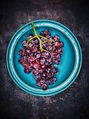 Red grapes on a blue plate against a grey background