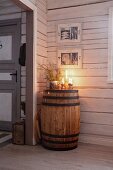 Kerzendeko auf einem alten Holzfass in einer Holzhütte