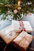 Gifts wrapped in vintage-style packaging below Christmas tree