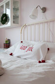 Embroidered cushion with pompoms on corners on metal bed