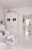 Two wreaths on doors of old cupboard in living room and view into hallway