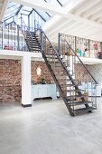 Steel stairs leading to two gallery levels in loft apartment with concrete floor and rustic brick wall