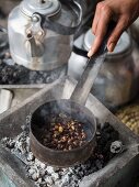 A woman roasting green coffee beans at a traditional coffee ceremony in Ethiopia