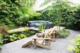 Terrassenplatz mit Holzliege und Gartenteich neben berankter Sichtschutzwand