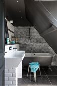Freistehende Badewanne an Mosaikfliesenwand unter grauer Dachschräge