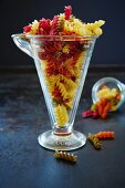 Colourful fusilli pasta in a measuring cup and a glass