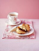 A scone with jar, clotted cream and a cup of coffee