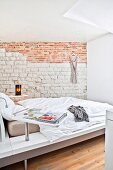Blick ins helle Schlafzimmer mit Designerbett und Sichtmauerwerk