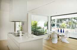 View across island counter to round dining table and panoramic windows