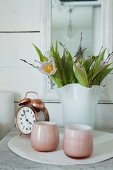 Pink tealight holders, alarm clock and tulips in white vase