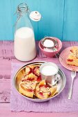 Yeast cake with plums and crumble in front of a bottle of milk