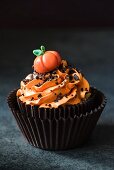 A halloween cupcake with orange buttercream icing and a pumpkin