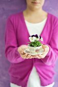 Viola planted in coffee cup held by child