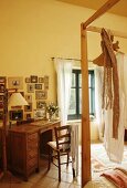 Vintage desk and wooden chair below gallery of pictures in country-house bedroom