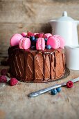 Schokoladenkuchen mit tropfender Schokoladenganache, frischen Beeren und rosa Macarons