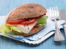 A fish burger with chilli sauce, tomatoes and salad