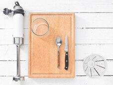 Kitchen utensils: a hand blender, a glass, cutlery and a measuring cup