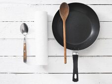 Kitchen utensils: a spoon, kitchen roll and a frying pan