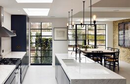 Island counter with marble counter and dining area in modern kitchen of loft-style apartment