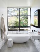 Helles, minimalistisches Bad mit freistehender Badewanne und schwarzen Fensterrahmen