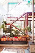 Orange scatter cushions on couch in comfortable lounge area in front of staircase in loft apartment with glass façade