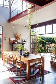 Solid-wood table in dining area of bright loft apartment with open terrace doors