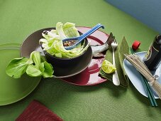An arrangement of salad, fish, noodles and soy sauce from Asia