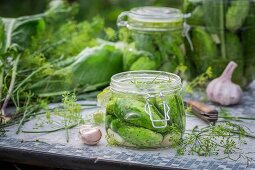 Pickled gherkins in glass jars on a garden table