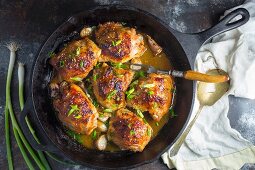 Chicken thighs with garlic and spring onions in a frying pan