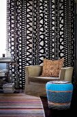 Mixture of patterns: zebra-patterned cushion on armchair in front of black and white curtain