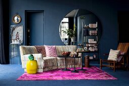Hot-pink rug and large round mirror in dark blue living room