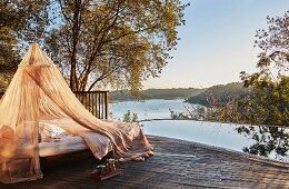 Relax-Liege mit Moskitonetz am Pool mit Panorama-Blick