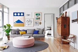 Gray couch with pillows against white, wood-clad wall with picture gallery in bright living room