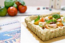 Salty tart with cream cheese, pesto, olives, pine nuts and fresh tomatoes (Liguria, Italy)